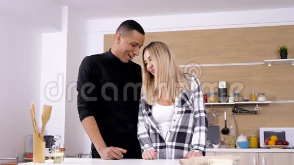 一对漂亮的年轻夫妇在厨房互相拥抱大笑视频的预览图