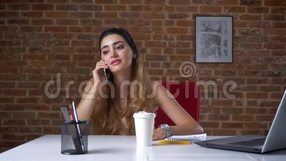 美丽的白种人女孩正在喝着白色的纸杯在桌面上聊天视频的预览图