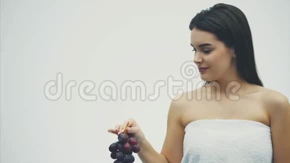 这个漂亮的女孩瘦了吃着健康的水果一个年轻漂亮的女人拿着成熟的葡萄花束的肖像和真实的视频的预览图