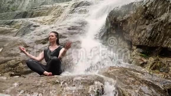女人在石头上做瑜伽旁边有瀑布视频的预览图