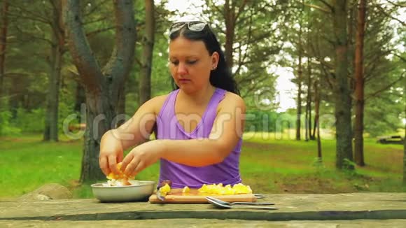 公园里的一个女人正在野餐时放一片橘子片做水果沙拉视频的预览图