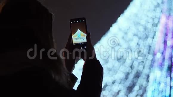 女人在电话里的照片主要城市圣诞树新年庆祝活动视频的预览图