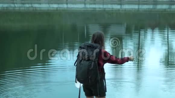 年轻的嬉皮士女士在冒险时缓慢地向山湖投掷石块视频的预览图