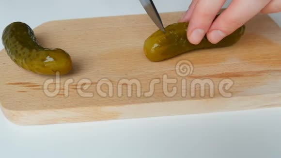 女性用黑色陶瓷刀在乡村菜板上切割腌制的罐装黄瓜视频的预览图