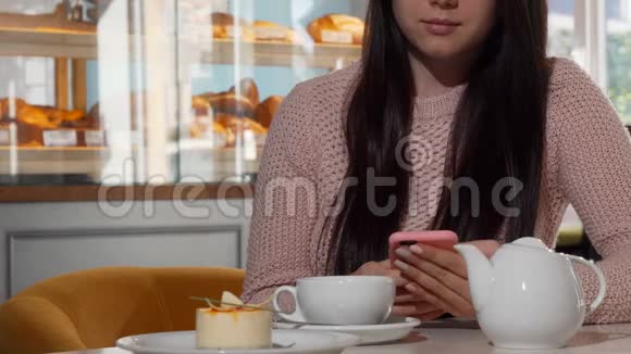在咖啡店喝热茶的时候用智能手机看不出来的女人视频的预览图