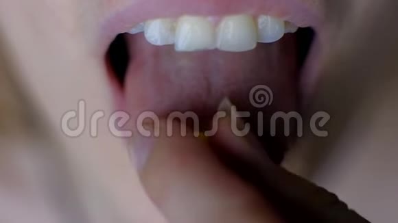 雌性的手把药片涂在他的舌头上视频的预览图