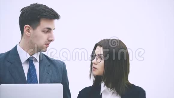 年轻的商务夫妇站着看着笔记本电脑里的东西讨论着重要的问题思考着视频的预览图