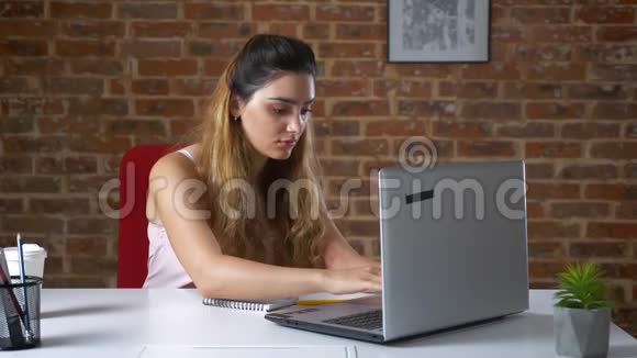 集中工作的白种人妇女正在寻找她的笔记本电脑和使用是在坐在桌子旁喝酒视频的预览图