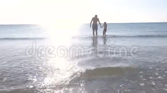 爸爸和儿子在日落时正在海边散步在海里游泳视频的预览图