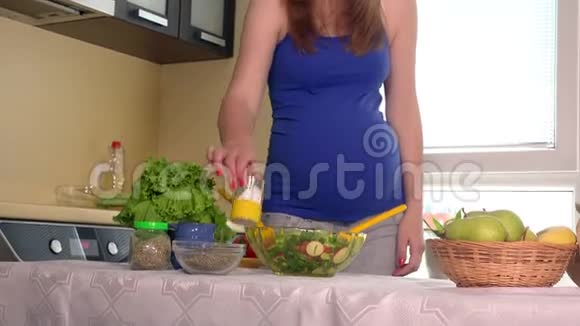 孕妇在玻璃碗中倒入盐和混合生态天然蔬菜沙拉视频的预览图