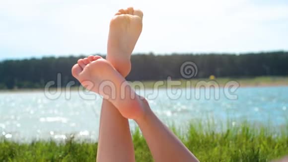 女子双脚特写放松享受阳光明媚的夏日假日假期湖视频的预览图