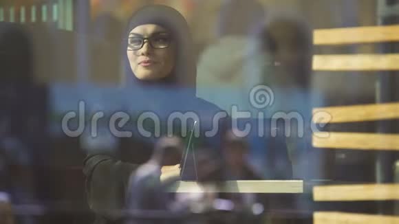 穿着头巾的女人在咖啡馆里看着窗户自由的穆斯林女流视频的预览图