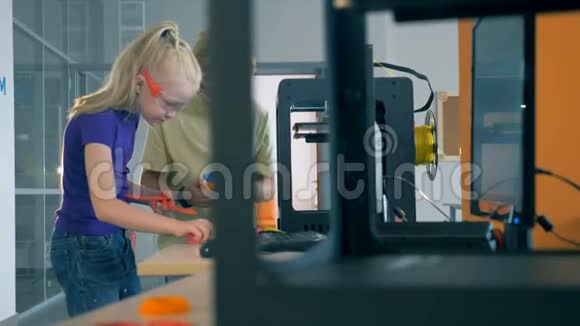 孩子们用3D打印机工作男孩和女孩在一个有印刷设备的科学实验室工作视频的预览图