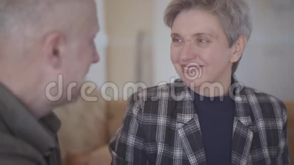 成年男子在房间里坐在沙发上用巧克力棒对待成熟的妻子家庭关系视频的预览图