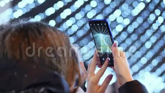 女人在电话里的照片主要城市圣诞树新年庆祝活动视频的预览图