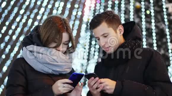 美丽的一对夫妇在下雪的夜晚圣诞节和新年使用移动应用程序视频的预览图