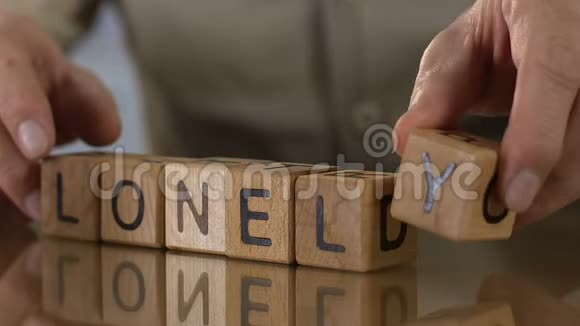 孤独的年长的男人在做木头方块的字人们在退休的家里视频的预览图