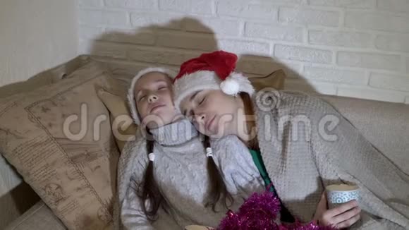 戴着圣诞老人帽子的孩子们在沙发上睡在毯子下等待圣诞老人肖像关门视频的预览图