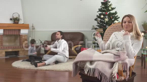 坐在摇椅上拿着信用卡的漂亮女人父亲和小儿子在玩无人机幸福家庭视频的预览图