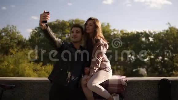 幸福的年轻夫妇在街上用手机自拍而女孩坐在栏杆上漂亮情侣自拍视频的预览图