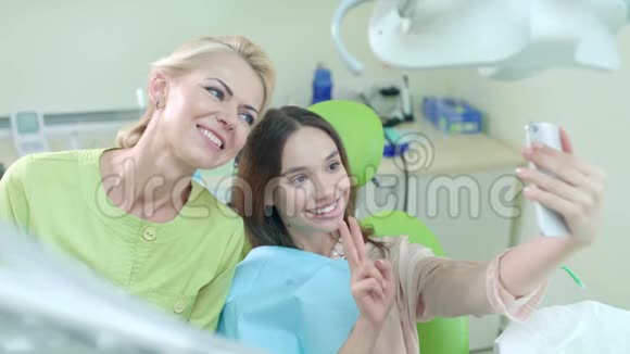 微笑医生和病人在牙科办公室自拍显示v号的女人视频的预览图