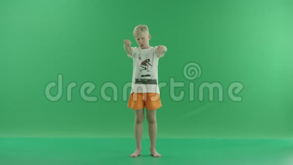 一个身穿便服的金发小男孩正竖起大拇指他站在绿色屏幕前视频的预览图