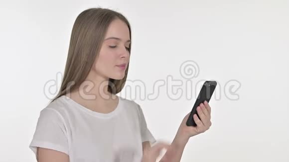 美丽的年轻女子在智能手机上庆祝白色背景视频的预览图