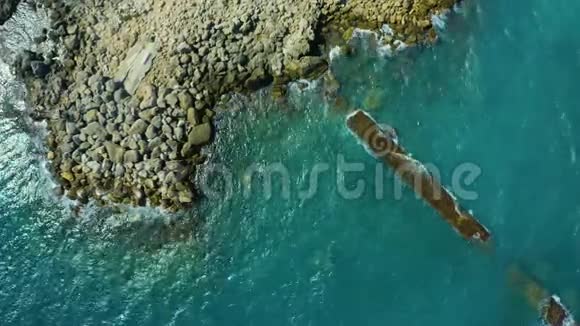 从无人驾驶飞机上俯瞰卓越的海洋岩石岩石和海浪美丽的蓝色海浪拍打着视频的预览图