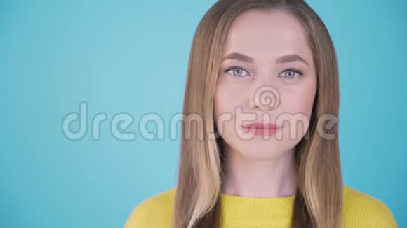 特写肖像蓝色背景下冷静的女孩孤立的背景在左边刻字的地方4K视频的预览图