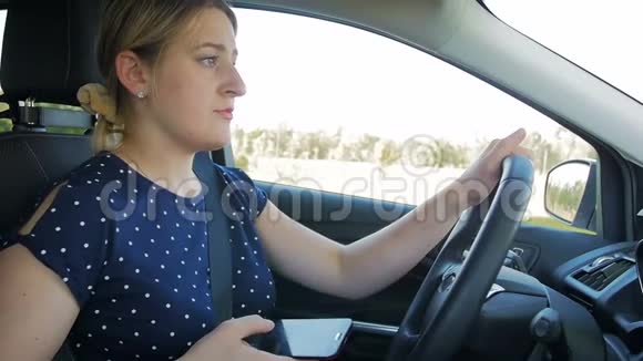 驾驶汽车时年轻女性使用智能手机的慢动作镜头请使用免提车辆以确保安全视频的预览图