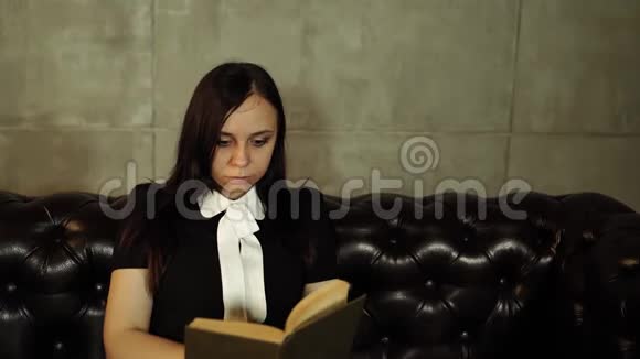 女人在沙发上看书20多岁的肖像妇女在明亮的沙发上休息和坐着还在看书视频的预览图