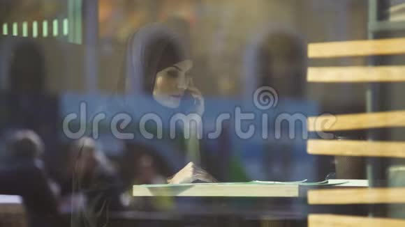 戴头巾的女人在咖啡馆里寻找合同叫合伙人自由的穆斯林女士视频的预览图