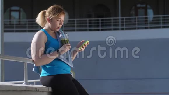 超重妇女慢跑者喝绿色冰沙视频的预览图