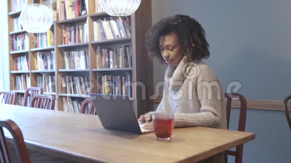 坐在咖啡店用手提电脑的临时女学生视频的预览图