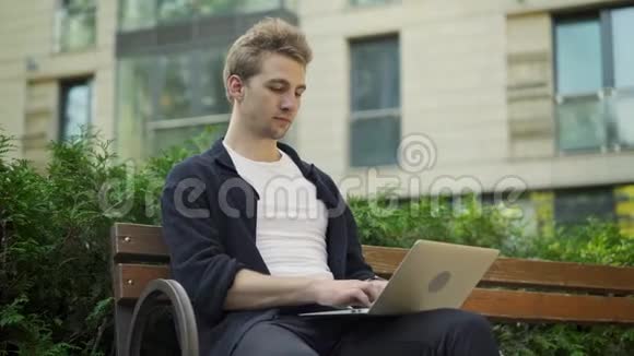 年轻人在外面打手提电脑检查手表视频的预览图