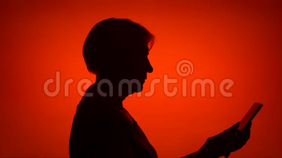 高级女性剪影在红色背景下使用手机女的脸做自拍视频的预览图