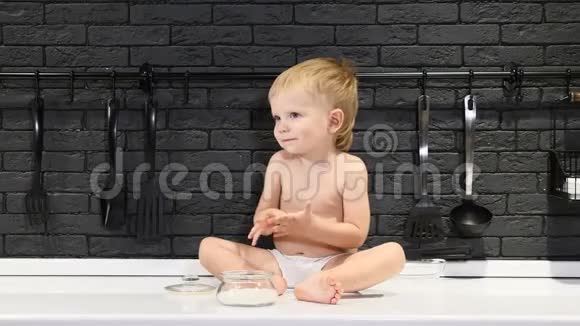 快乐的童年概念可爱的小男孩坐在桌子上用手指品尝糖和糖果4k视频的预览图