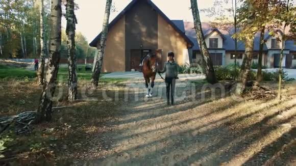 戴头盔的年轻女子骑着马从马厩里出来开始骑马视频的预览图