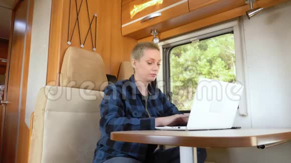 一个女人坐在汽车之家的桌子旁使用笔记本电脑视频的预览图