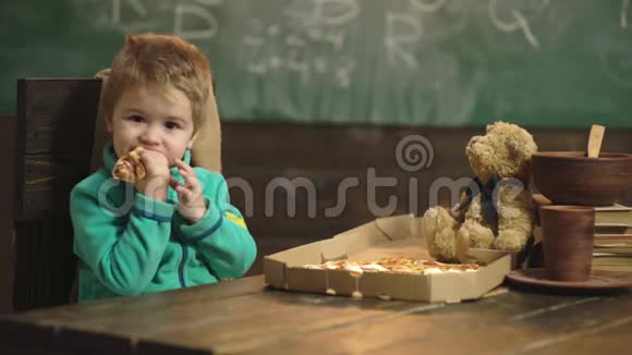 可爱的白人小男孩吃披萨在木制背景下吃披萨的男孩营养概念美味的披萨宝贝视频的预览图