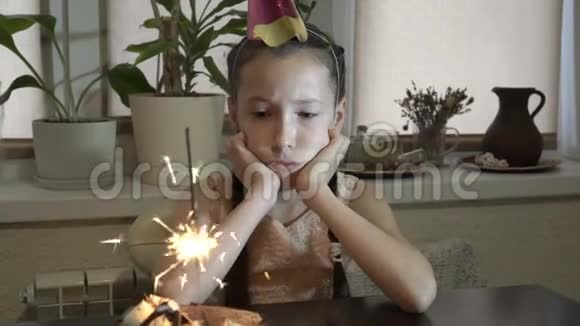 一个悲伤的小女孩的肖像看起来像一个闪闪发光的她坐在蛋糕前的一张桌子旁让他休息视频的预览图