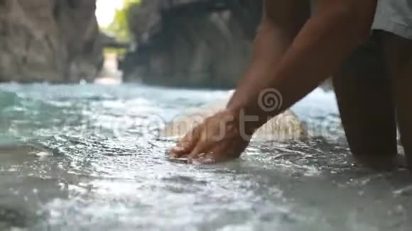 无法辨认的徒步旅行者用清澈的凉水在山河里洗手一个站在河中的家伙视频的预览图