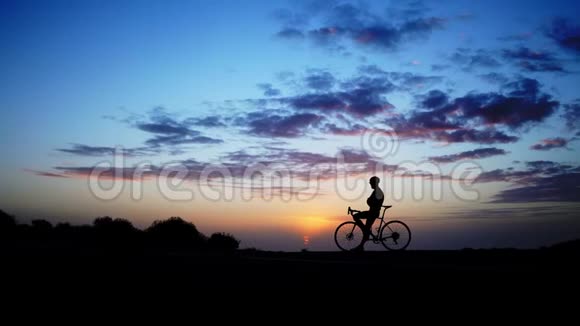 山地自行车手到达山顶庆祝在惊人的黄昏灯光下他把自行车举到天空视频的预览图