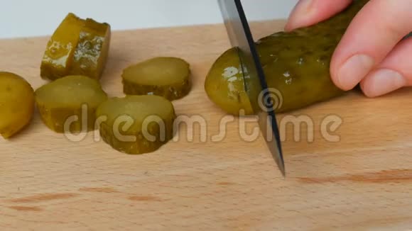 女性用黑色陶瓷刀在乡村菜板上切割腌制的罐装黄瓜视频的预览图