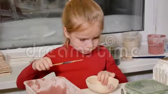 有创意的小女孩用刷子把她的生陶瓷碗上釉视频的预览图