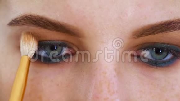 蓝眼睛红头发的迷人年轻女子的近照脸得到专业的眼妆视频的预览图