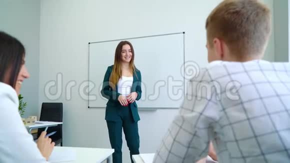 在白板旁辅导高中生的年轻微笑女教师视频的预览图
