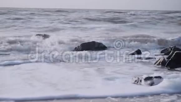 海浪覆盖着海中的花岗岩黑色石头对抗天空视频的预览图