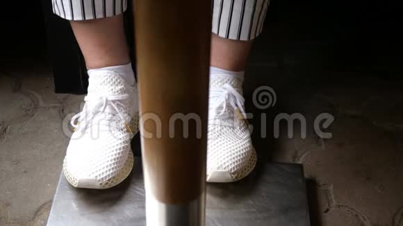 一个穿着白色运动鞋和黑白条纹裤子的女人的腿在桌子下面跺脚视频的预览图