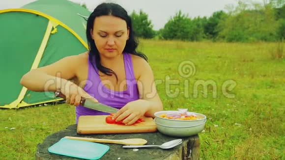 帐篷附近的一个女人在木板上切了红色番茄片视频的预览图